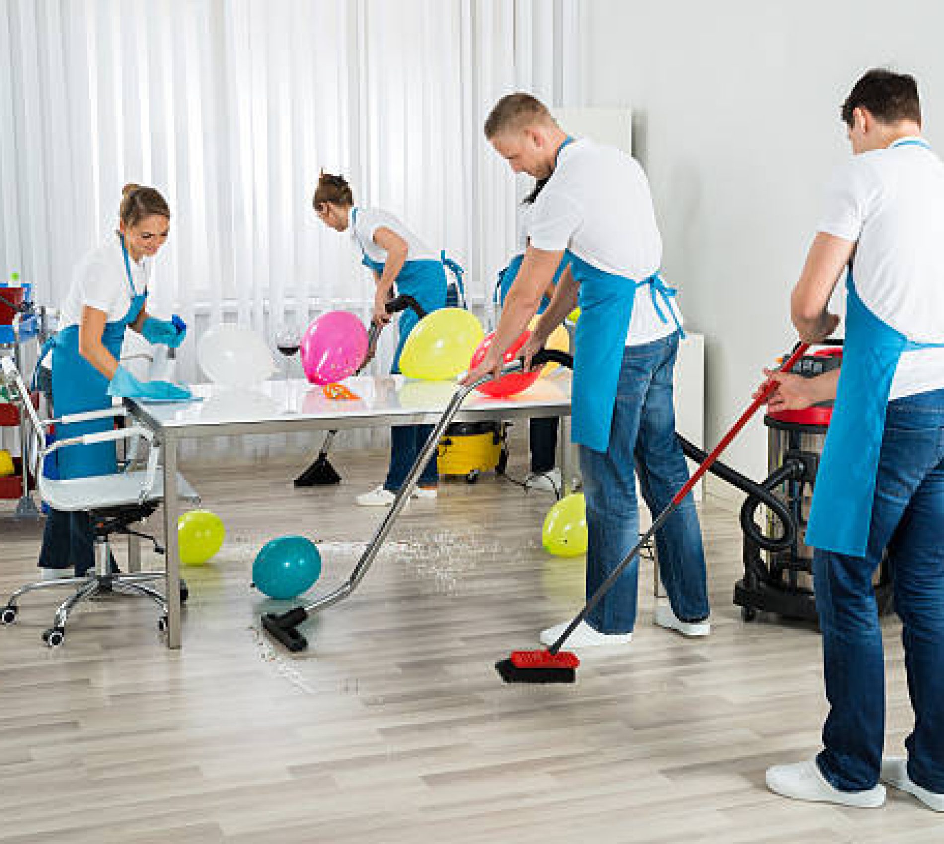 Group Of Male And Female Janitors Cleaning The Office After Party